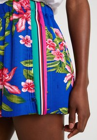 Bloemen shorts in het blauw met roze en groene patronen, met een geplooid ontwerp en contrasterende zijkanten in meerdere kleuren.