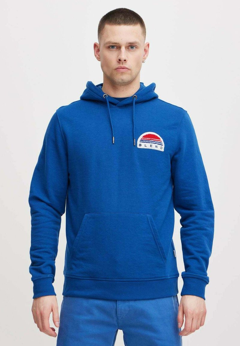 Felpa con cappuccio blu, tasca frontale, cordino e logo ricamato con strisce rosse e bianche in un design circolare.