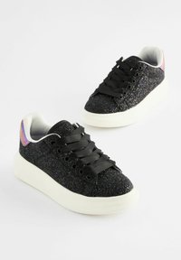 Schwarze Glitzer-Sneaker mit weißer Sohle, schwarzen Schnürsenkeln und schimmernden Akzenten an der Ferse. Die strukturierte Oberseite sorgt für visuelles Interesse.
