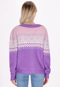 Pārmērīgs džemperis ar lilā un rozā krāsu shēmu, ģeometriskajiem rakstiem, ribotām piedurknēm un maigu tekstūru.