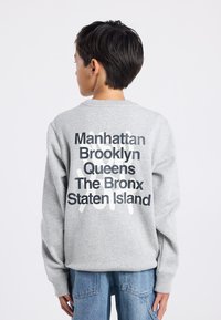 Felpa grigia con testo audace in bianco e nero che elenca i quartieri di New York sul retro, con scollatura a girocollo e vestibilità comoda.
