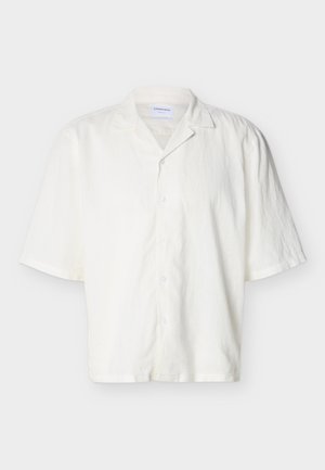 Chemise blanche à manches courtes avec col campagnard, boutonnée, fabriquée en tissu léger, présentée sur un fond neutre.