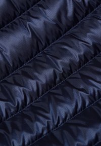 Marinblått quiltat tyg med horisontell sömnad och ett subtilt rutmönster, som visar en vadderad, texturerad yta.