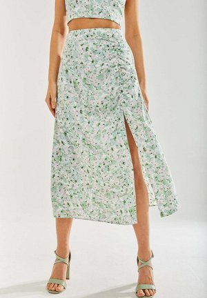 Floral midi skirt in light green and white with a side slit, crafted from lightweight fabric; paired with strappy green high-heeled sandals.