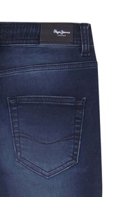 Jeans de mezclilla azul oscuro con un bolsillo trasero que presenta costuras curvas y una etiqueta negra inscrita con "Pepe Jeans London" en la cinturilla.