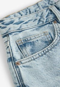 Ljusblå denimjeans med en urtvättad finish, detaljstikningar och en liten bakficka med en metallrivet-accents.