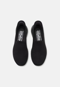 Czarne buty wsuwane wykonane z siateczkowego materiału, z okrągłym noskiem, posiadające wyściełaną wkładkę i elastyczną gumową podeszwę.