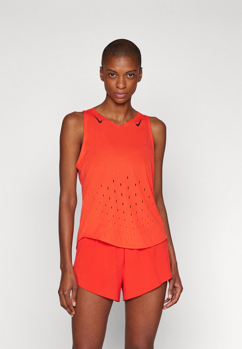 Ärmelloses Sportoberteil und Shorts in leuchtendem Orange, mit strukturiertem Design und Belüftungslöchern, minimalen schwarzen Akzenten an den Schultern.