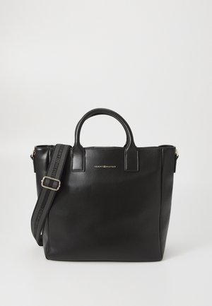Black leather tote bag with dual handles and a detachable shoulder strap, featuring gold logo detail and smooth textured finish.