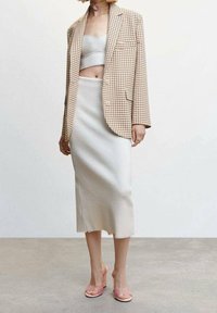 Blazer à carreaux beige, crop top blanc ajusté, jupe crème mi-genou et sandales à talons roses ; textures lisses et lignes épurées.