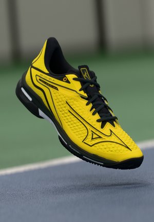 Yellow athletic shoe with textured upper, black accents, and sturdy sole. Features laces and a brand logo prominently displayed.