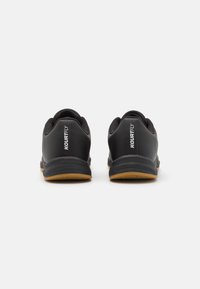 Black athletic shoes featuring a smooth synthetic upper, textured mesh paneling, a cushioned sole, and a gum rubber outsole.