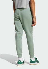 Sweatpants in light green cotton blend, featuring tapered legs and elastic cuffs, paired with green sneakers and white socks.