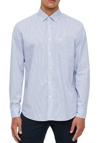 Camicia a scacchi blu chiaro con colletto, maniche lunghe, taschino sul petto e logo discreto sulla tasca. Tessuto misto cotone.
