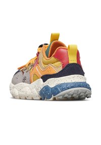 Sneaker multicolore con suola robusta, linguetta gialla, lacci arancioni e un mix di materiali in suede e tessuto mostrata da un'angolazione laterale posteriore.