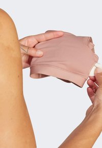 Prenda de tela rosa claro con una textura suave, mangas cortas y un diseño ajustado. Incluye una banda elástica blanca para un ajuste seguro.