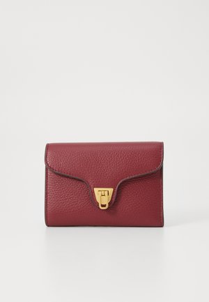 Red textured leather wallet with a flap closure and gold hardware. Notable for its smooth edges and compact rectangular shape.