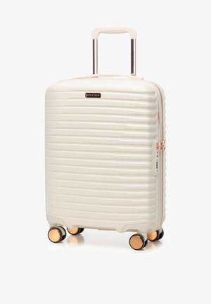 Valigia rigida bianca con scanalature orizzontali testurizzate, dettagli in oro rosa, doppie ruote e manico retrattile per una facile manovrabilità.