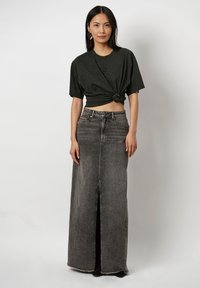 Zwart cropped T-shirt met geknoopt front, gecombineerd met een hooglopende, enkel-lange, donkergrijze spijkerrok met een split aan de voorkant.