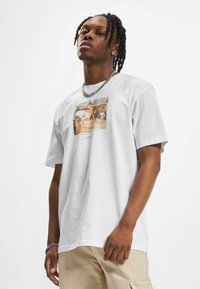 Camiseta de algodón blanca con un estampado gráfico central que representa a personas bailando en un hermoso fondo. Manga corta y corte relajado.