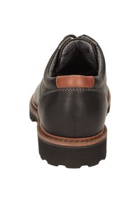 Scarpa in pelle nera con un accento in pelle marrone sul tallone, dotata di una suola in gomma nera testurizzata e di un design cucito sulla tomaia.