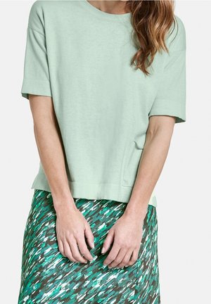 Lichtgroene, kortärmige katoen t-shirt met een ronde halslijn, gecombineerd met een groen en bruin geprint rokje met abstracte penseelstreken.