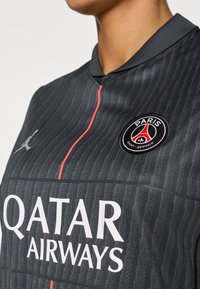 Must jalgpallimärkidega särk, millel on peened vertikaalsed triibud, krae ja punased aktsendid. Kuvab Paris Saint-Germaini ja Qatar Airwaysi logod.