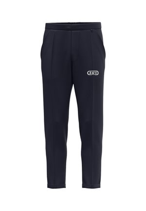 Pantaloni casual neri da uomo a gamba affusolata con tasche frontali e logo JAKO SPORT sulla coscia destra, mostrati frontalmente su sfondo bianco.