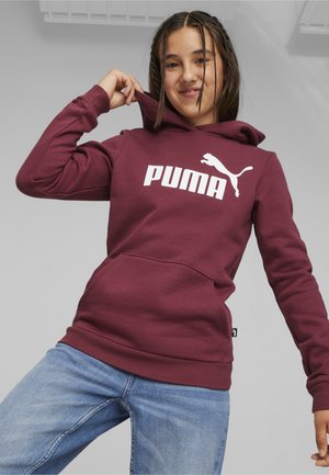 Sudadera con capucha de color marrón burdeos con logotipo en blanco de "PUMA" y silueta de gato, que cuenta con un bolsillo frontal y puños acanalados. Combinada con jeans azules.