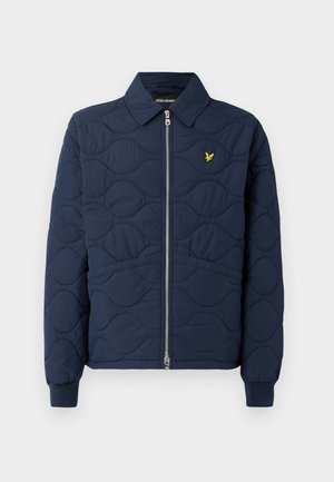 Navy quilted jacket with a zip front, pointed collar, ribbed cuffs, and a small gold logo on the chest. Smooth texture with wave patterns.
