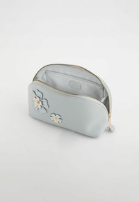Neceser de cosméticos de cuero azul claro con cremallera, adornado con dos apliques florales en crema y azul, y un interior liso.