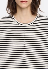 T-shirt rayé noir et blanc avec un col rond et une coupe droite, confectionné dans un tissu doux au toucher lisse.