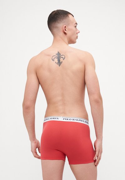 Boxers vermelhos em tecido elástico branco com o texto "POLO RALPH LAUREN". Design suave e ajustado, mostrado de costas.