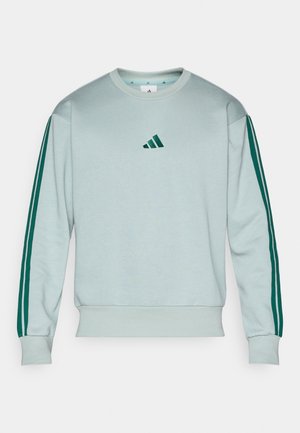 Svijetloplavi dukserica s zelenim prugama duž rukava i zelenim Adidas logom na prsima. Izrađena od mekog materijala s rebrastim manžetama.