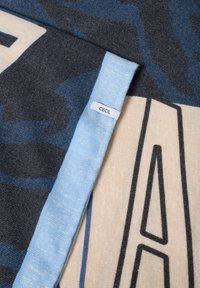 Cecilia-Decke mit einer weichen, gewebten Textur. Graues, blaues und cremefarbenes Farbschema mit einem auffälligen grafischen Design und hellblauer Umrandung.