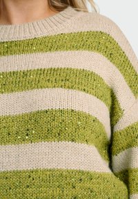 Groen en beige gestreepte trui gemaakt van zacht breiwerk, met horizontale strepen en pailletten voor extra textuur en detail.