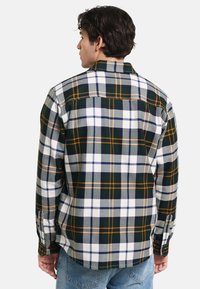 Zielona, biała i pomarańczowa koszula flanelowa w kratkę, z długimi rękawami, zapięciami na guziki i luźnym krojem. Wyraźny kontrastowy wzór w kratkę.