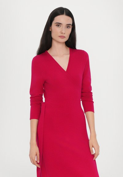 Rochie fucsia cu design în stil petrecut, mâneci lungi și fenta laterală. Textură netedă, decolteu în V și siluetă mulată.