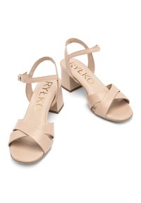 Beżowe sandały na obcasie z plecionym designem, krzyżującymi się paskami z przodu, zapięciem na kostkę z klamrą oraz niskim obcasem w kształcie bloku.