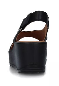 Sandalo con zeppa nera e apertura sul retro, dotato di una fascia in pelle liscia e di una soletta imbottita. Il tacco a zeppa è solido e leggermente curvato.