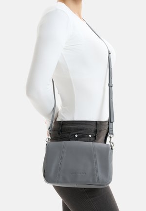 Graue Leder-Crossbody-Tasche mit verstellbarem Gurt, rechteckiger Form, sichtbaren Nähdetails und eingeprägtem Logo auf der Vorderseite.
