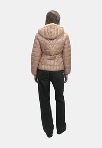 Giacca imbottita rosa chiaro con cappuccio, caratterizzata da un motivo trapuntato e una vestibilità strutturata. Indossata su jeans neri a vestibilità rilassata.