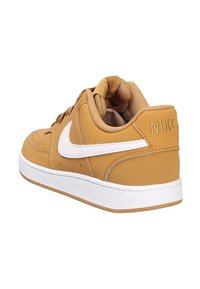 Nike sneakers i tan læder med en hvid swoosh, med en polstret krave og tekstureret tunge, sat på en hvid gummisål.