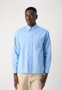 Lichtblauw overhem shirt met ruitpatroon, lange mouwen, een borstzakje en een standaardkraag. Gemaakt van gladde stof.