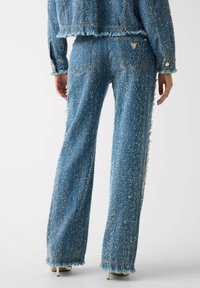 Pantaloni ampi in tessuto blu e strutturato con orli sfrangiati e dettagli laterali. Dotati di tasche posteriori e di un piccolo logo del marchio sulla vita.