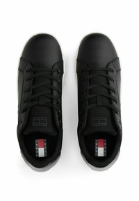 Zapatillas deportivas de cuero sintético negro con puntera redonda, suela blanca contrastante, lengüeta de malla y cordones negros; presenta el logo de la marca en la plantilla interior.