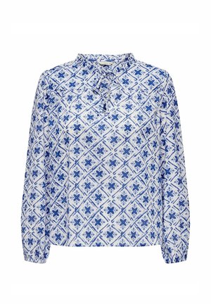 Blouse blanche à manches longues avec un motif floral bleu en forme de losange, encolure avec ouverture en trou de serrure et détail noué au col.