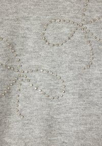 Tessuto a maglia grigio chiaro con motivi floreali sottili formati da piccole perline argentate rotonde disposte in petali contornati.