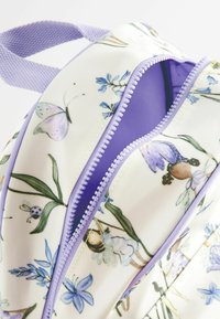 Rucsac cu un model floral, cu o bază crem, având accente mov, o suprafață texturată și un fermoar interior contrastant de culoare mov.