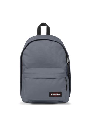 Mochila gris hecha de tela duradera, que cuenta con un amplio compartimento principal, un bolsillo frontal con cremallera y un asa en la parte superior para llevar. Presenta detalles en negro.